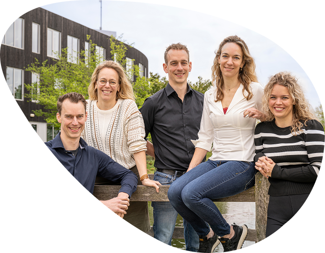 Vijf lachende mensen buiten bij modern gebouw.