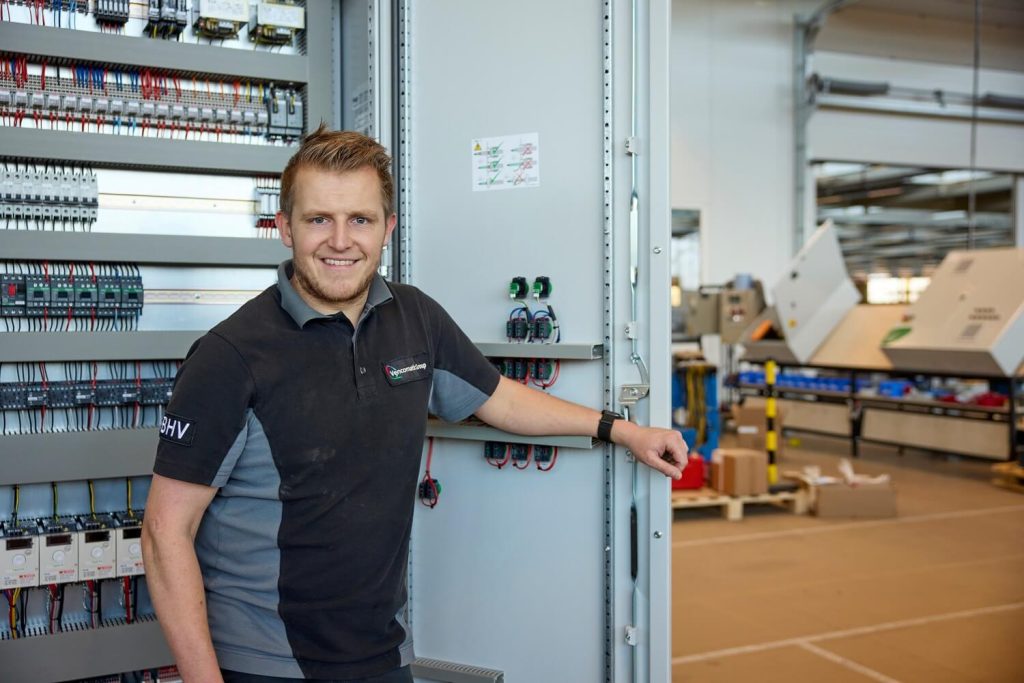 Man bij geopende elektrische kast in fabriekshal