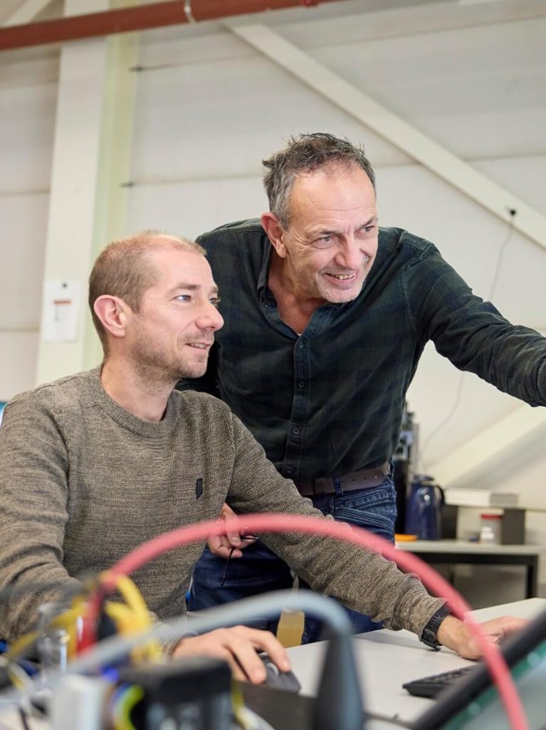 Twee mannen werken samen aan computer in kantoor.