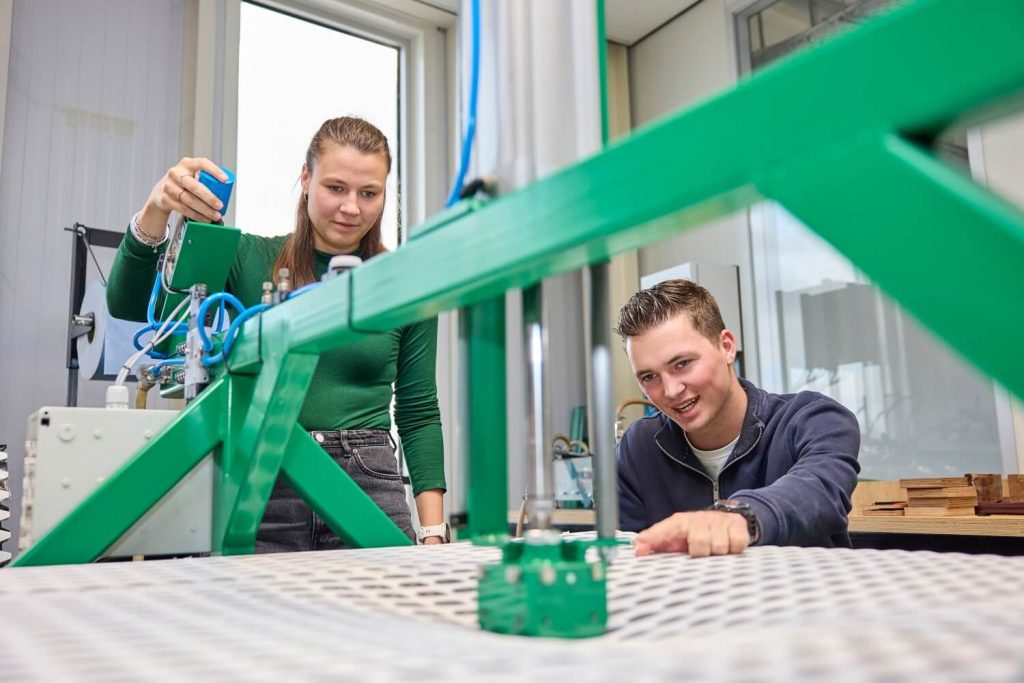 Twee studenten werken met groen apparaat in laboratorium.