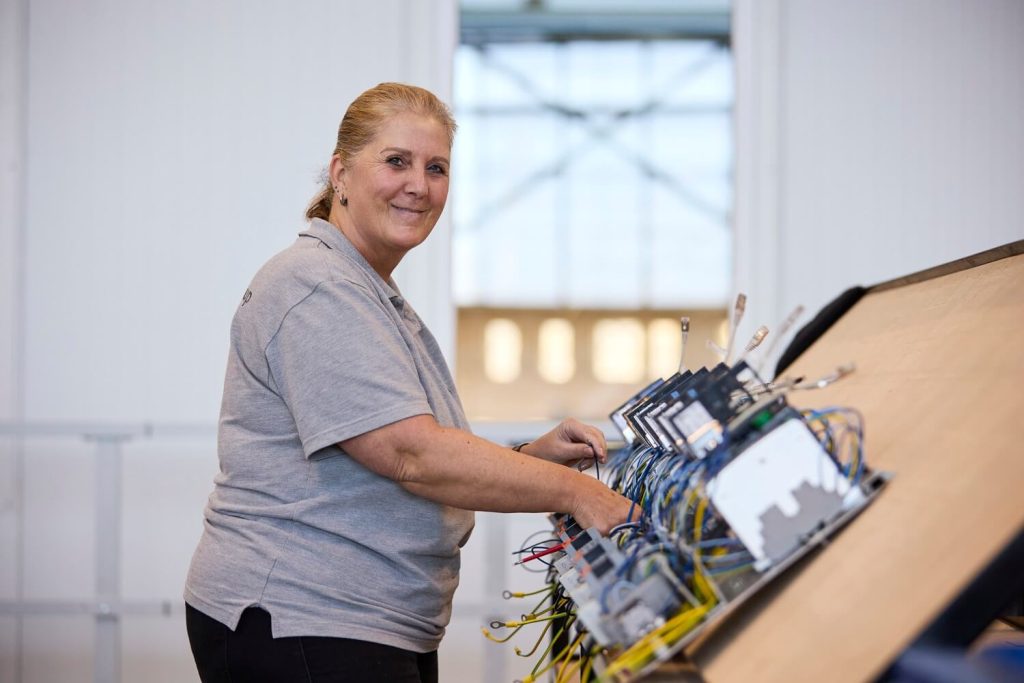 Vrouw werkt aan elektronica-installatie op werkplaats.