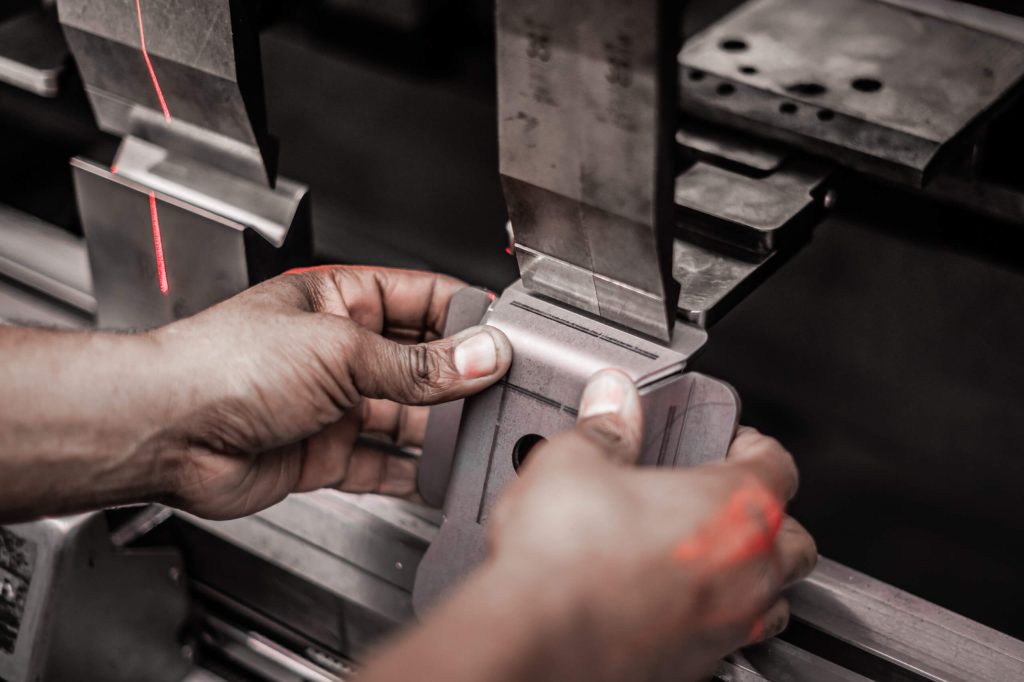 Handen werken met metaal in een machine