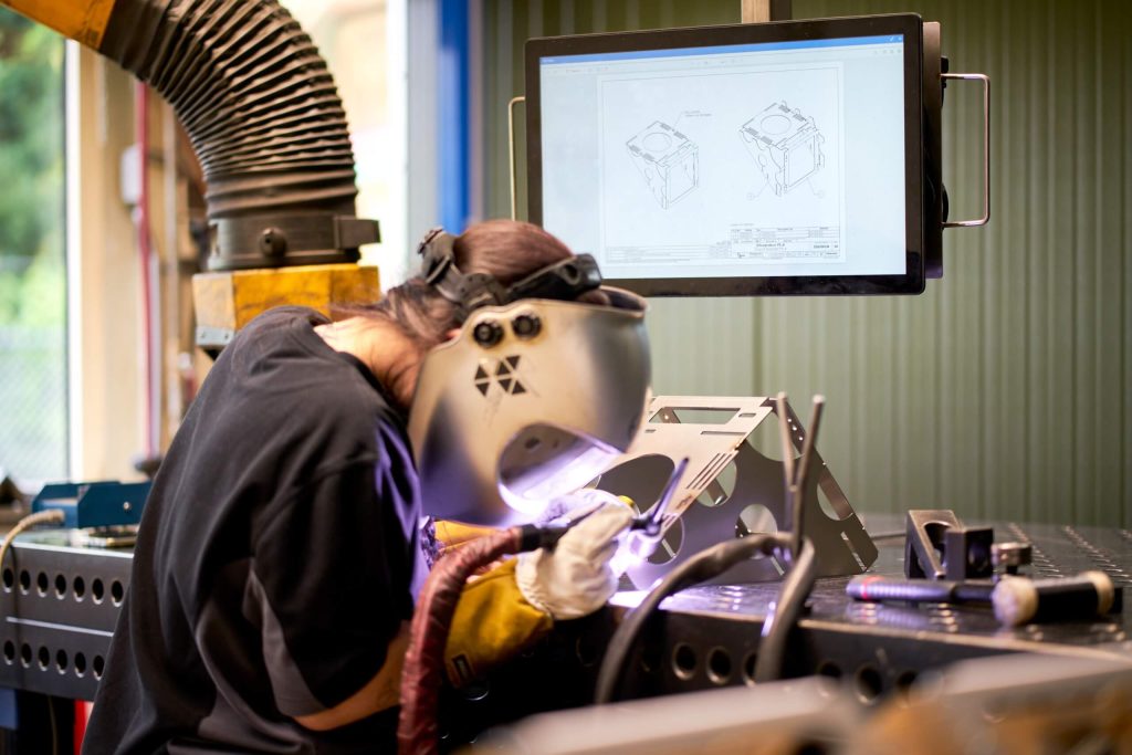 Lasser werkt aan metaal bij industriële werkbank.