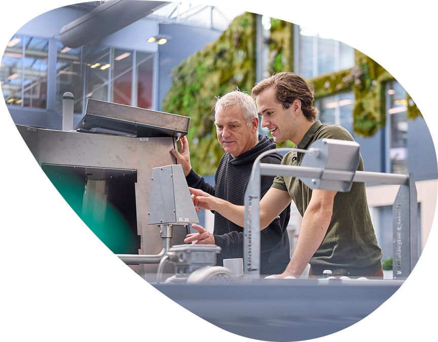 Twee mannen werken samen aan industriële machine.