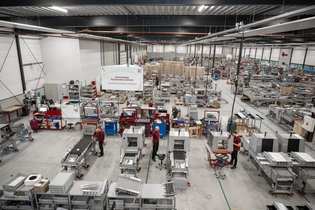 Productiehal met machines en werkende medewerkers.