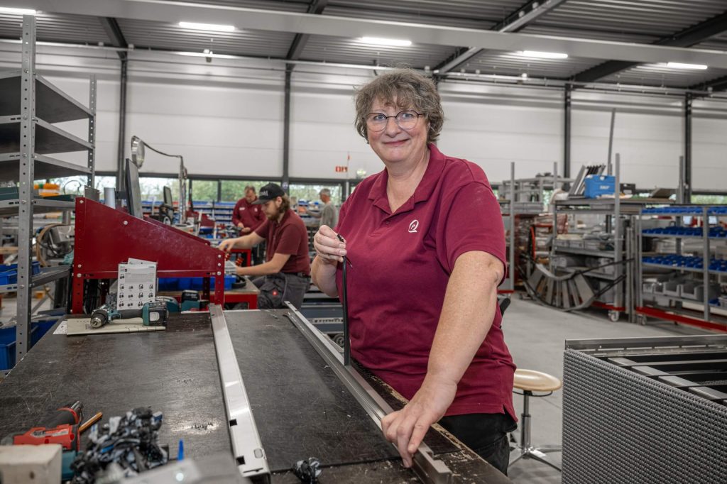 Vrouw werkt in een fabriekshal met machines.