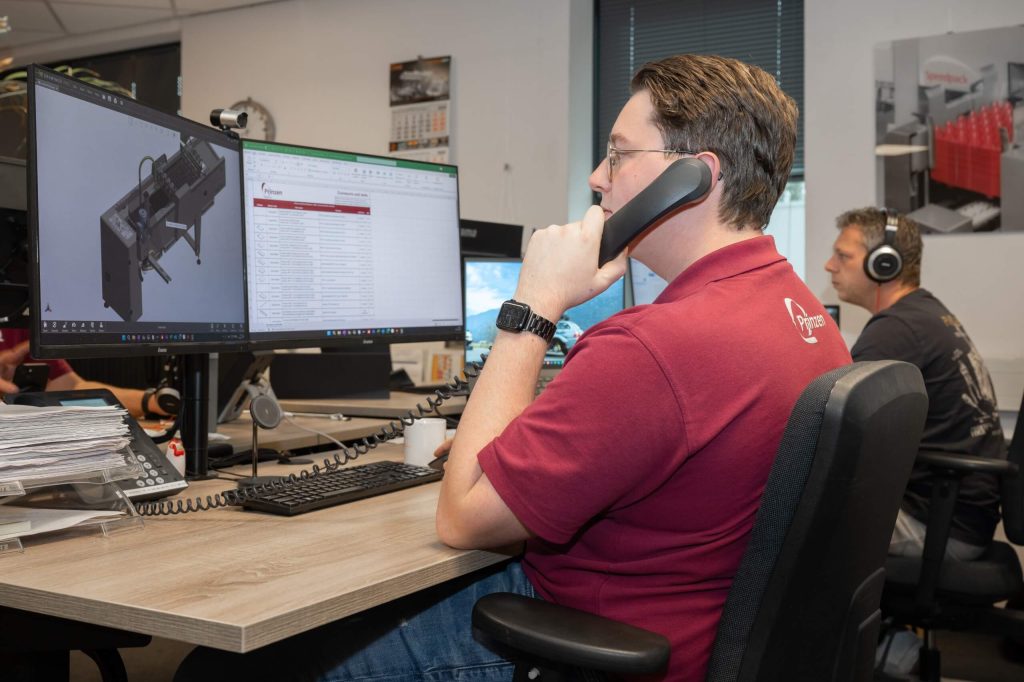 Man werkt op kantoor met computer en telefoon.