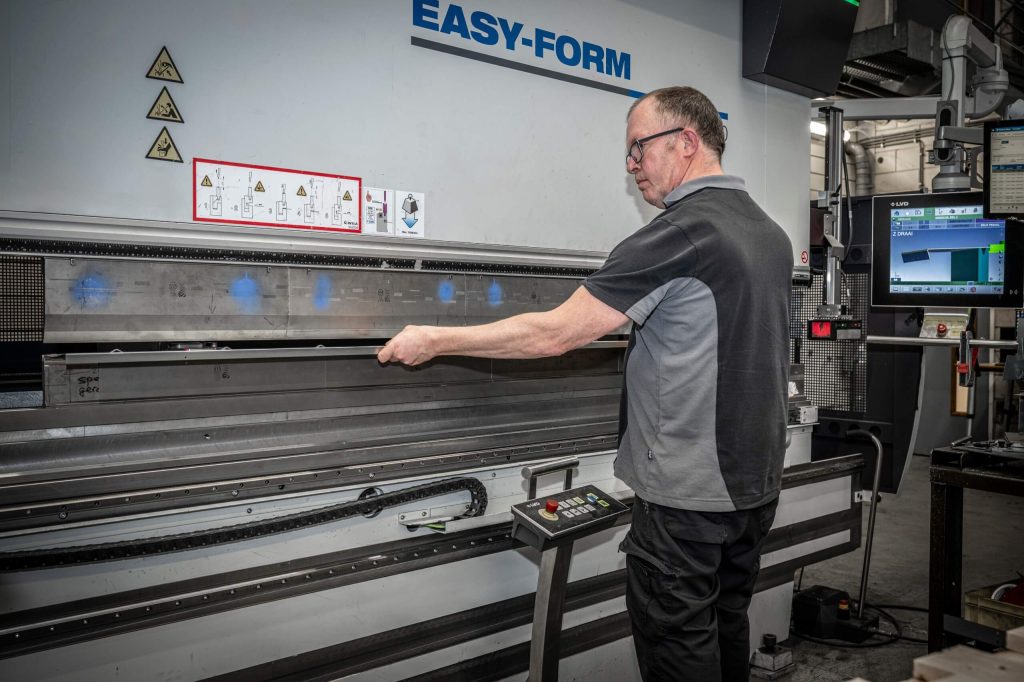 Man bedient buigmachine in fabriekshal.